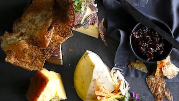 A variety of cheeses, crackers, and a glass of wine on a dark surface.