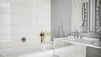 A modern bathroom with a large bathtub, two sinks, and a large mirror.