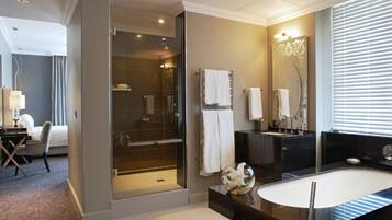 A modern bathroom with a glass-enclosed shower, a large bathtub, and a vanity with a mirror.