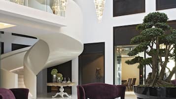 A modern interior with two plush armchairs, a round coffee table, and a large potted tree.