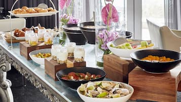 A buffet table with various food items, including fruits, vegetables, and desserts, arranged on wooden stands and glass containers.