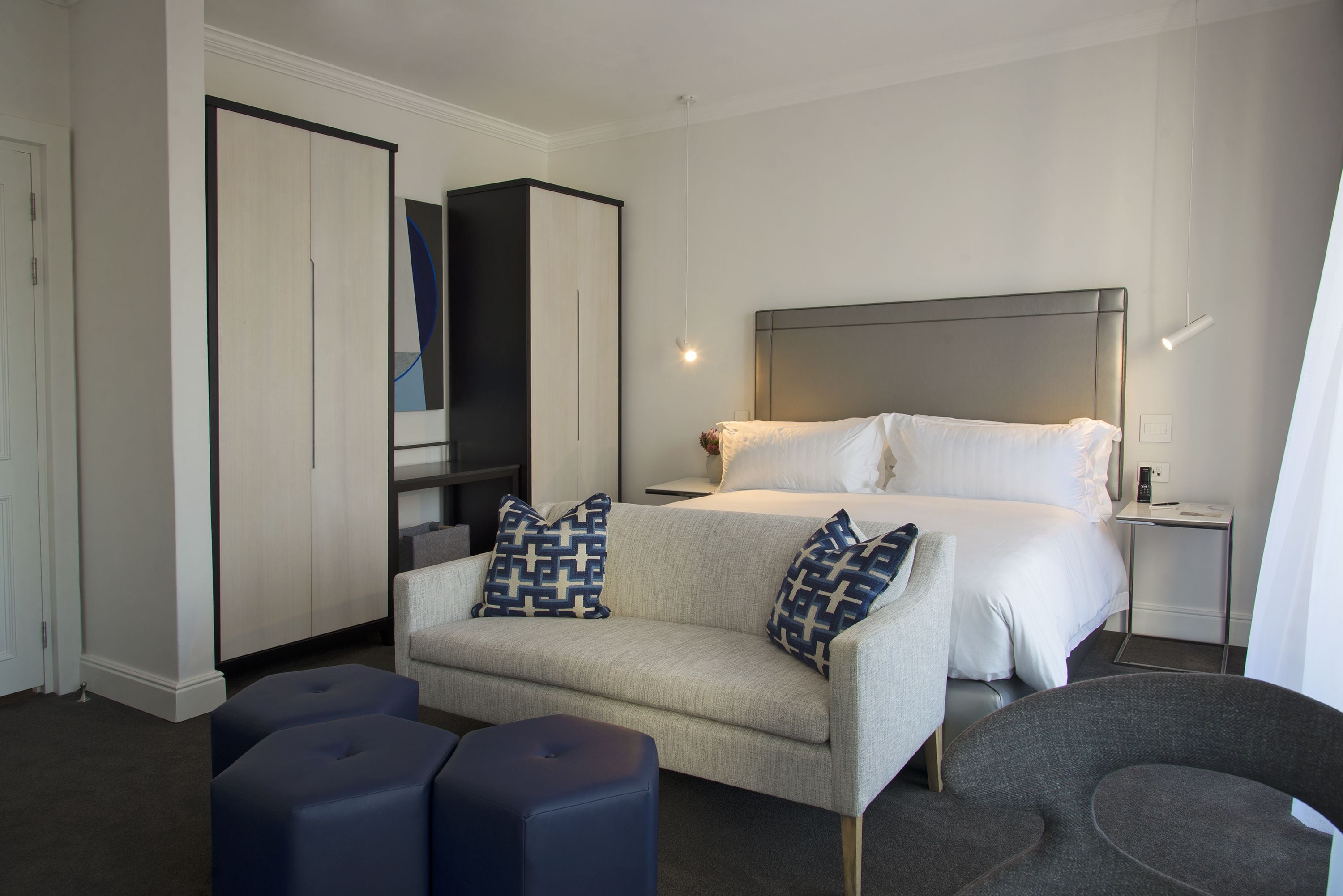 A modern hotel room with a bed, a sofa, a TV, and a wardrobe.
