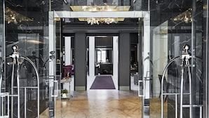 A modern lobby with marble floors, a central pathway, and glass doors leading to rooms. - Queen Victoria Hotel & Manor House by NEWMARK (Cape Town)