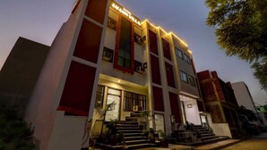 A multi-story hotel with a modern design, featuring a prominent entrance with steps and potted plants. - Hotel Anand Villa (Agra)