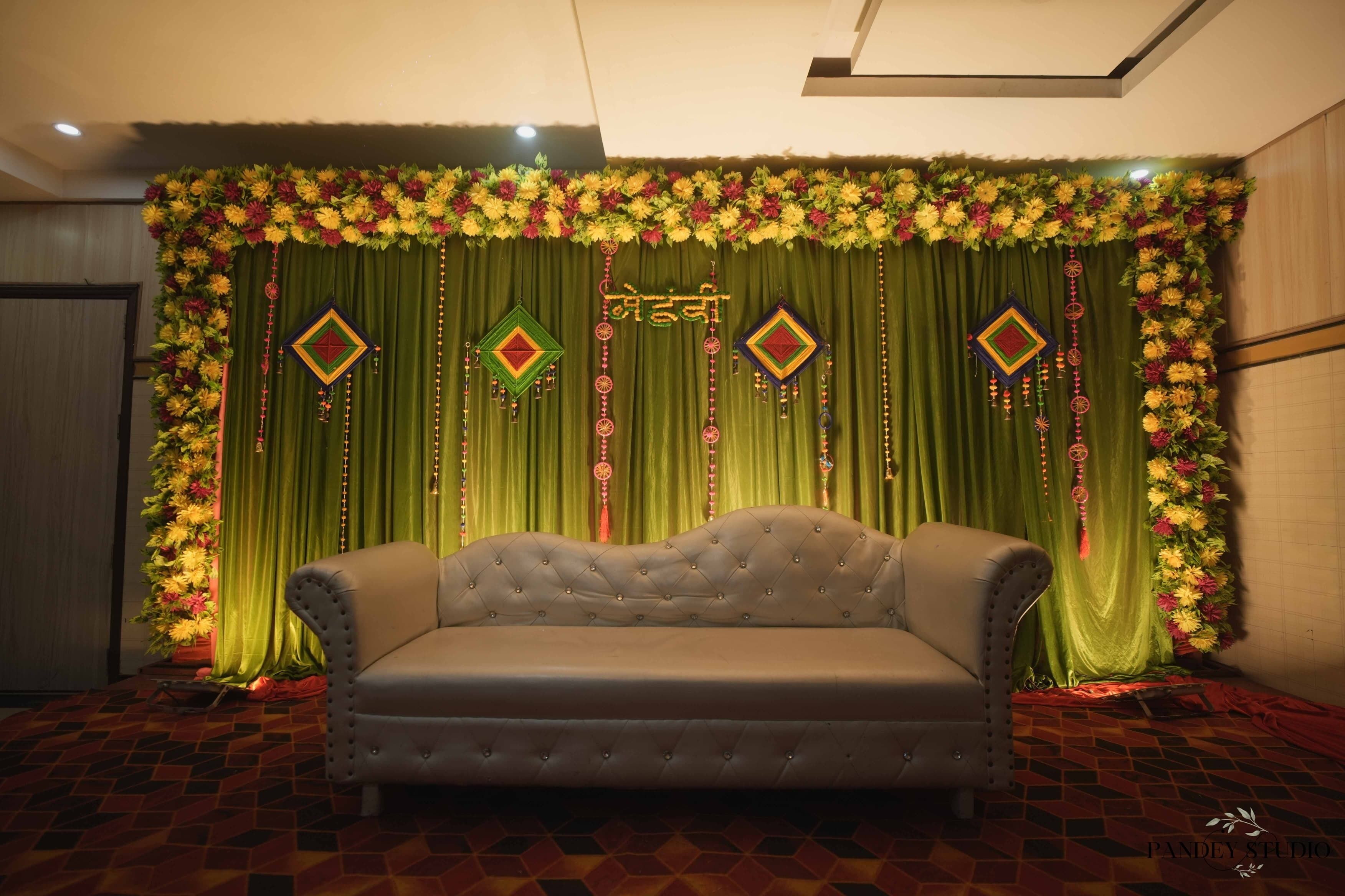 A room with a green curtain backdrop, a tufted sofa, and a patterned floor.