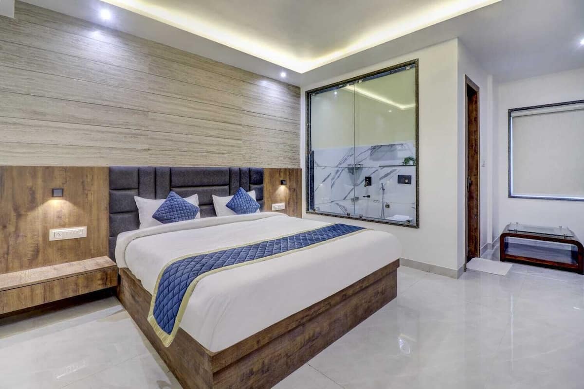 A modern bedroom with a large bed, wooden headboard, and a glass shower enclosure.