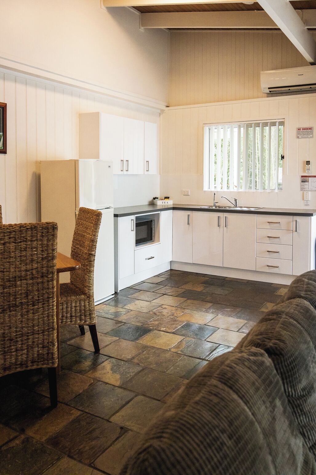 A compact kitchen with white cabinets, a built-in oven, and a window with blinds.