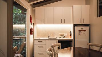 A modern kitchen with white cabinets, a built-in oven, and a dining area with a wooden table and chairs.