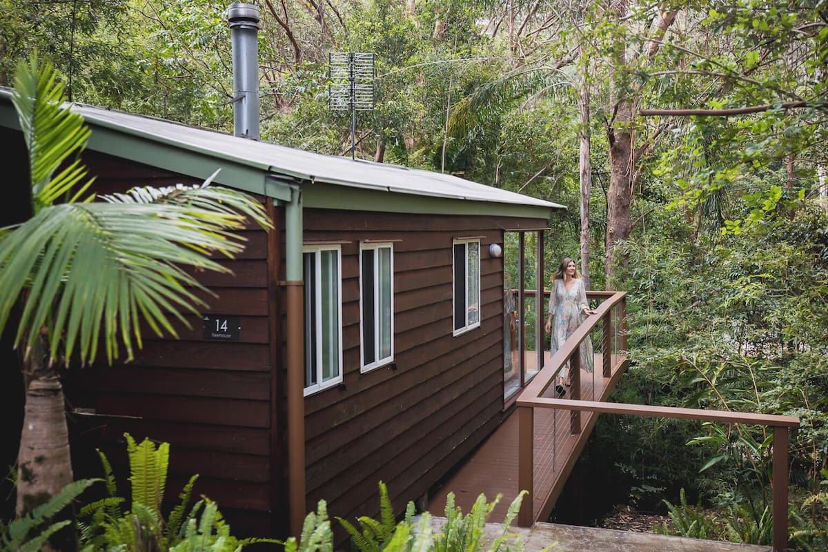 Eine Holzhütte mit Balkon, umgeben von dichtem Wald.