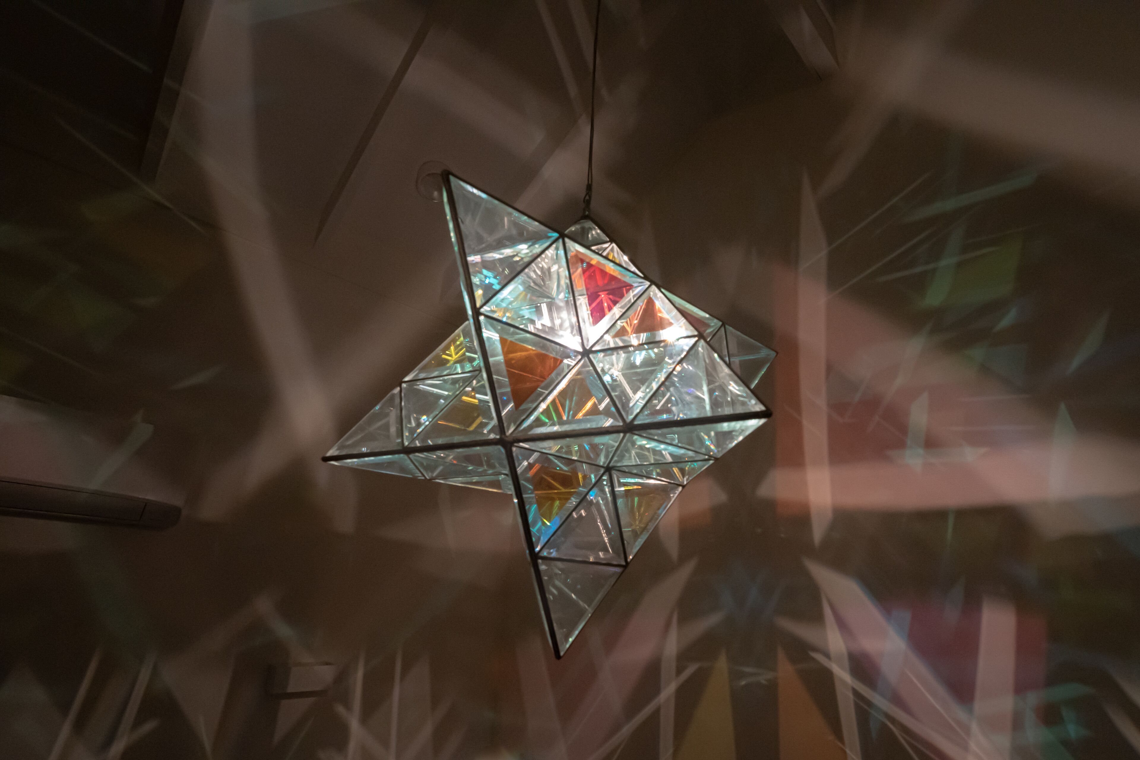 A geometric chandelier with multiple glass panels and a central light source.
