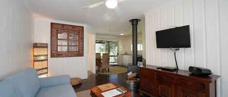 A living room with a blue sofa, a wooden coffee table, a television on a stand, and a fireplace.