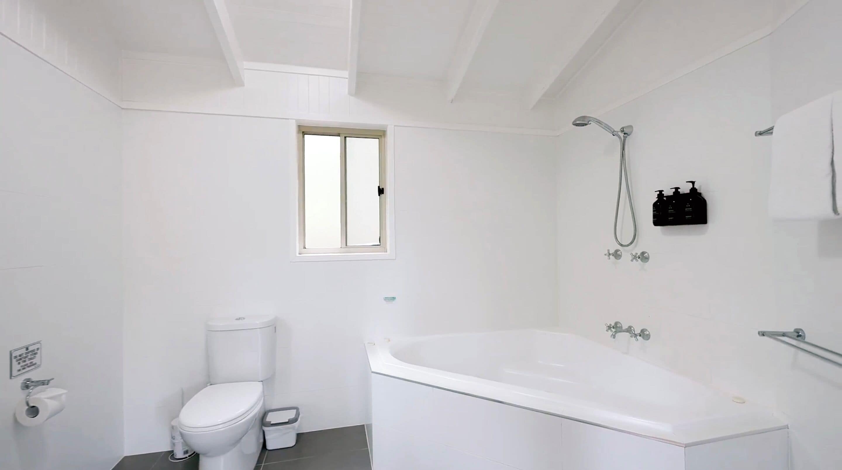 A modern bathroom with a toilet, bidet, and a bathtub.