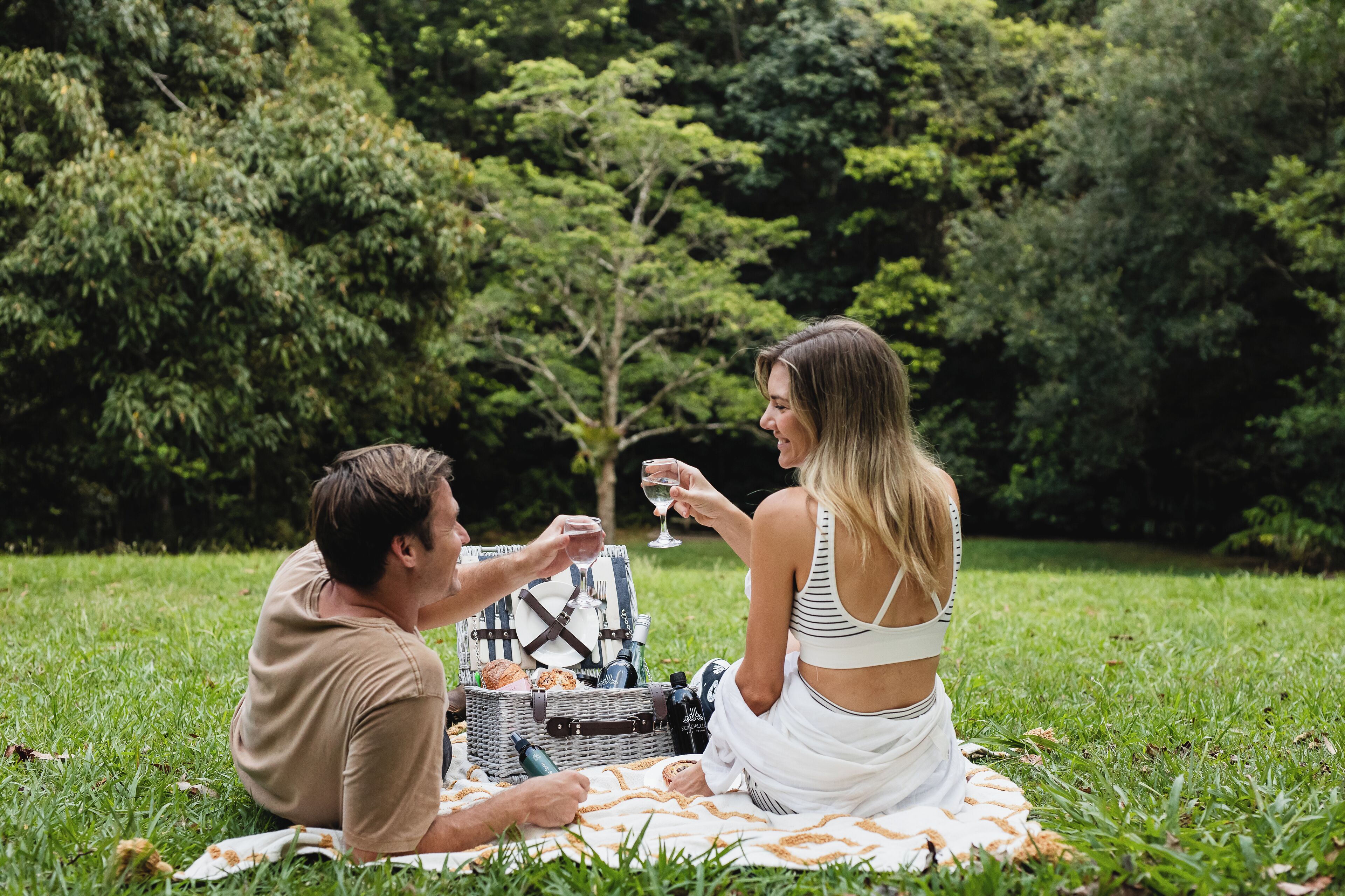 Una pareja sentada sobre una manta al aire libre, con una preparación para un picnic.