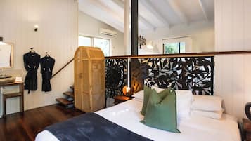 A bedroom with a bed, a wooden wardrobe, a mirror, and a staircase.