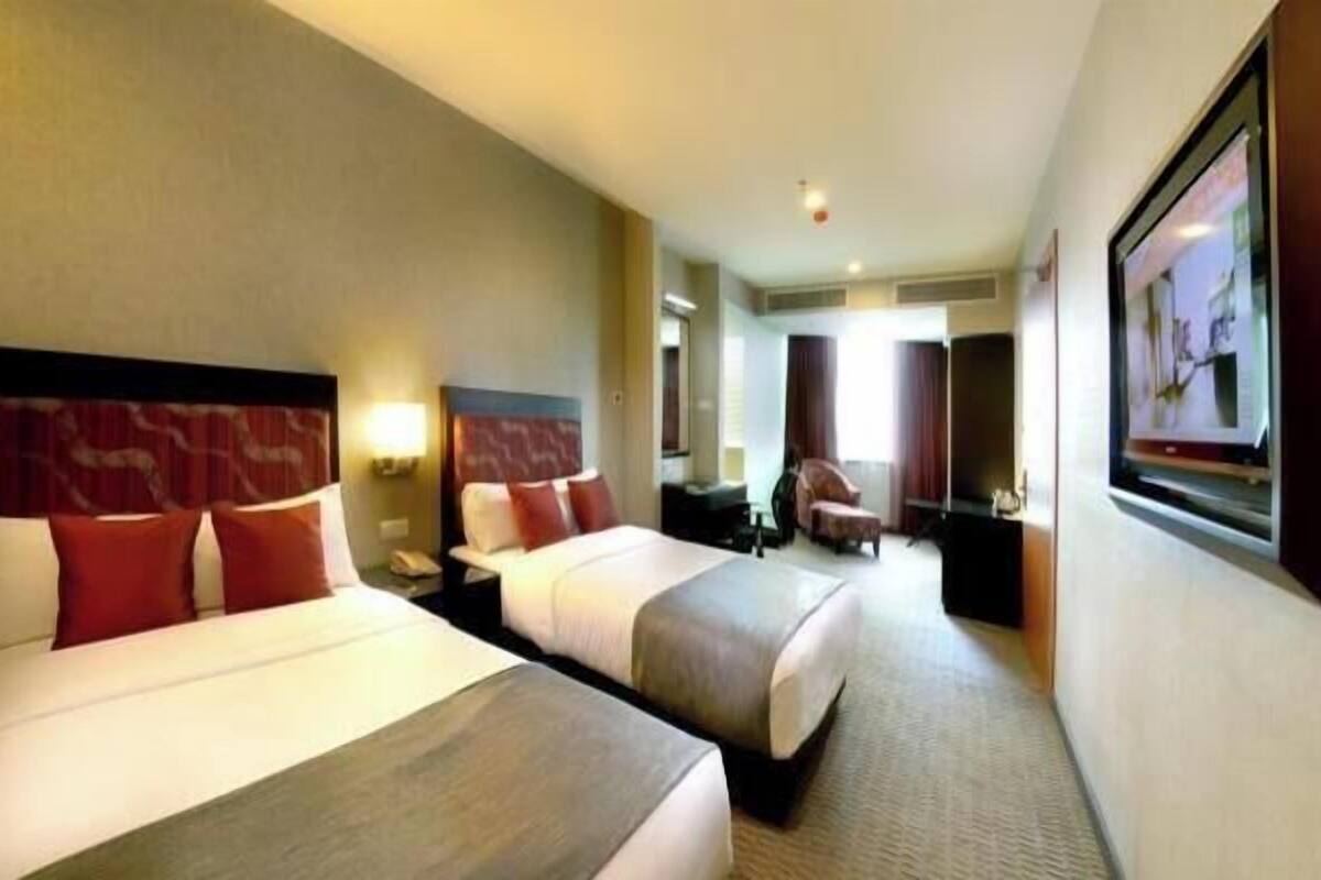 A hotel room with two beds, a TV, a desk, and a chair.