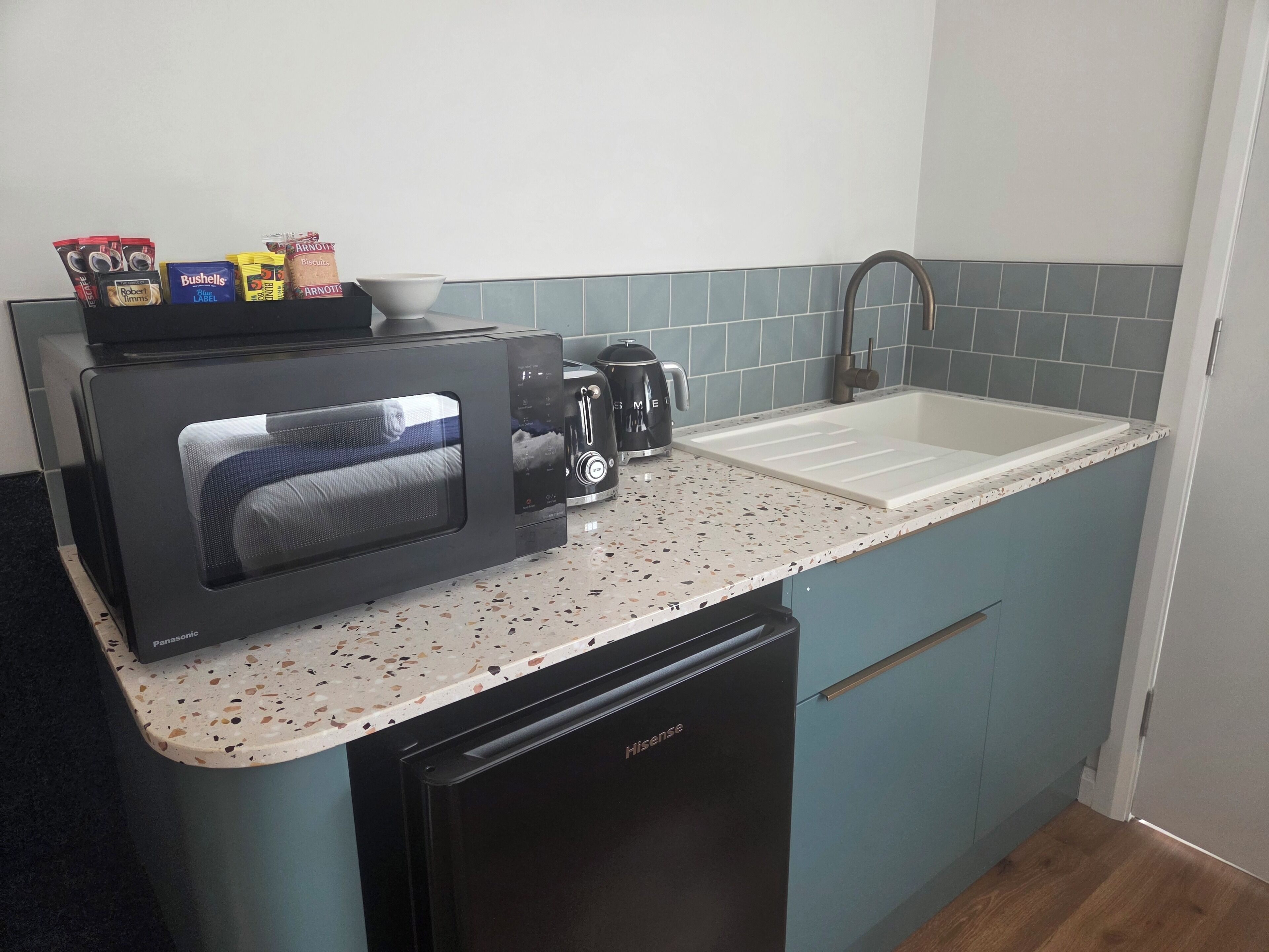 A compact kitchen with a microwave, toaster, and coffee maker on the countertop.