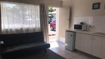 Un espacio habitable compacto con sofá, una kitchenette pequeña y vista a la calle.