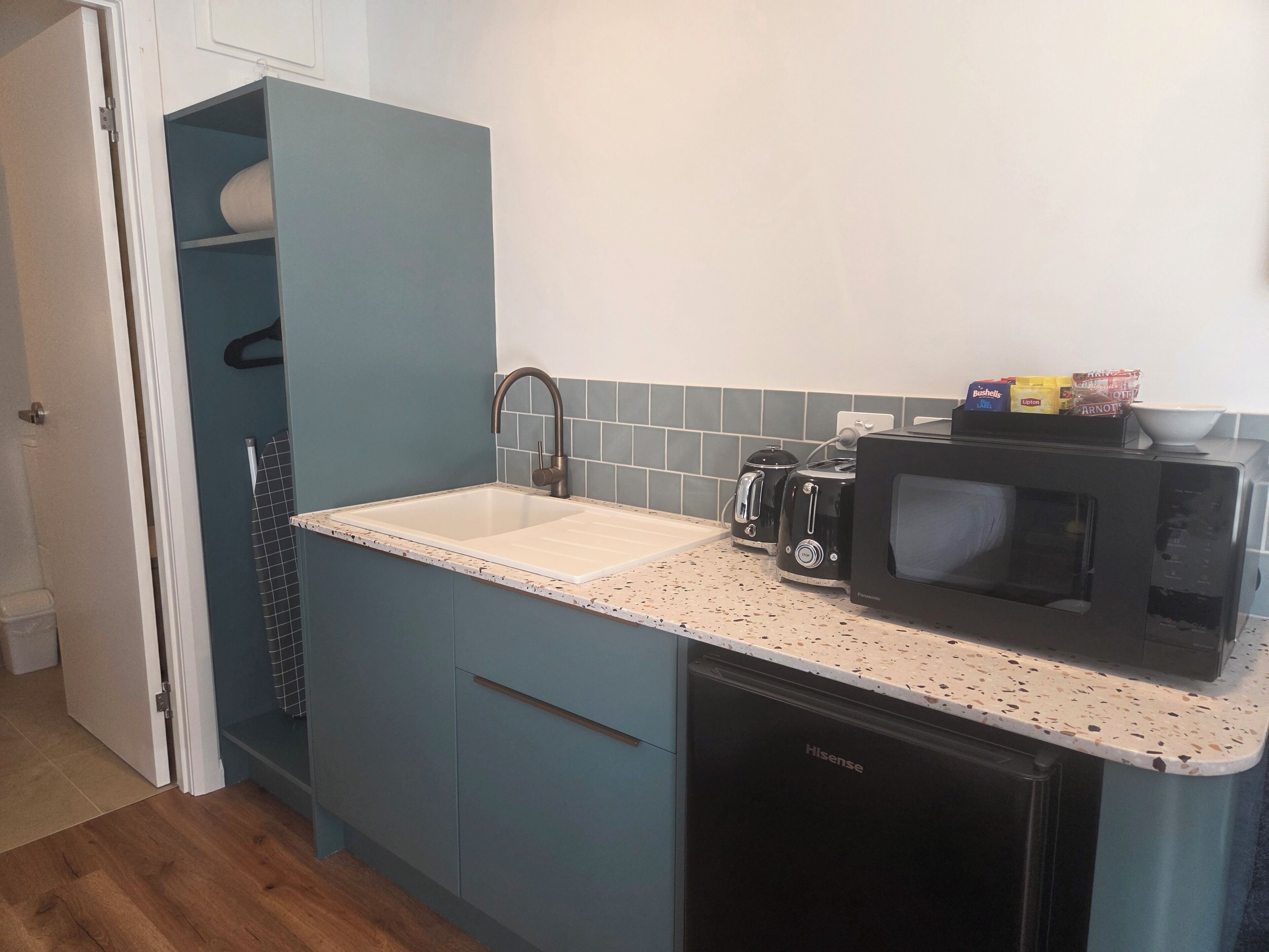 A compact kitchen with a sink, a microwave, a toaster, and a dishwasher.