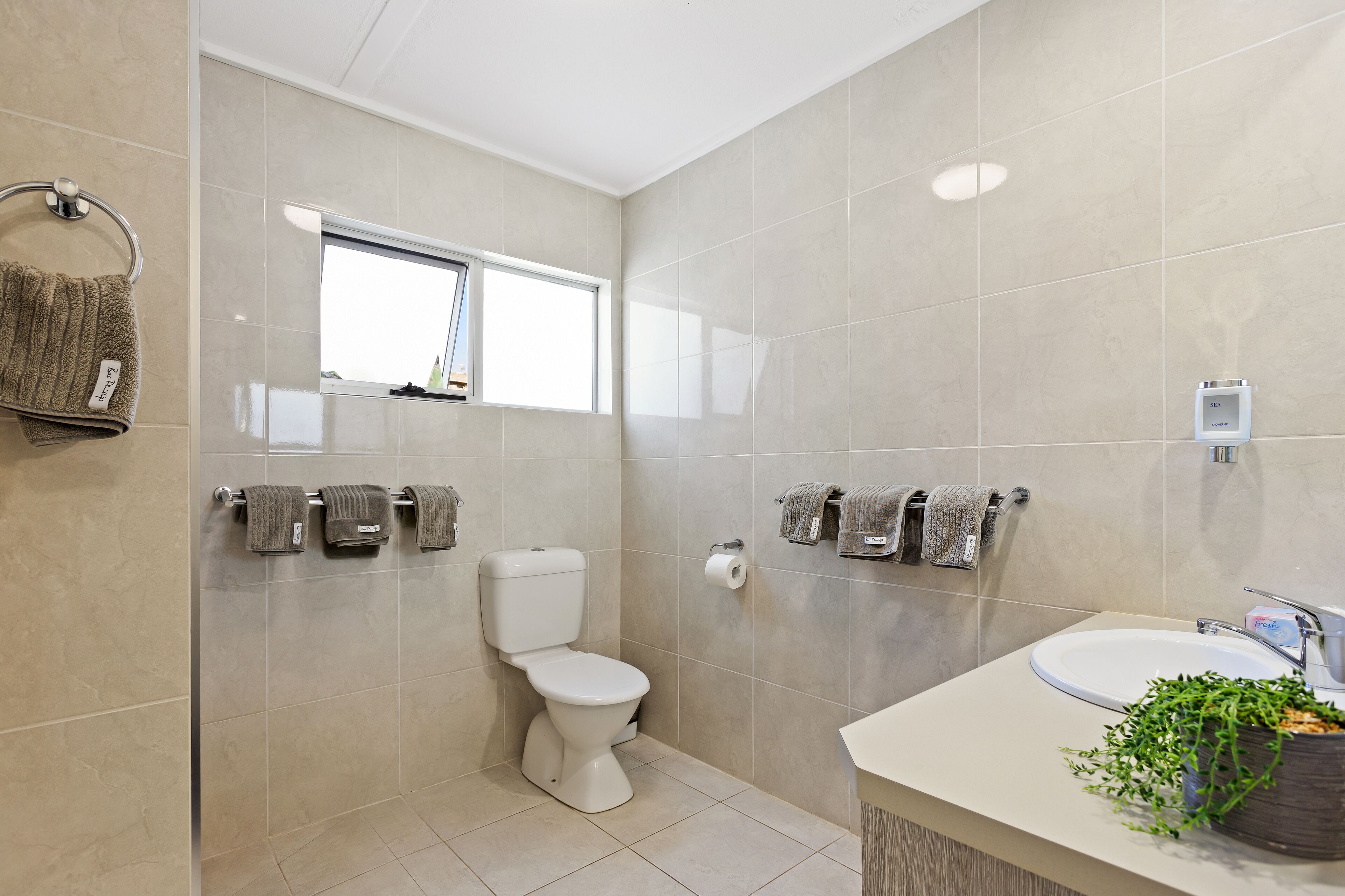 Een moderne badkamer met toilet, wastafel en handdoekhouder.