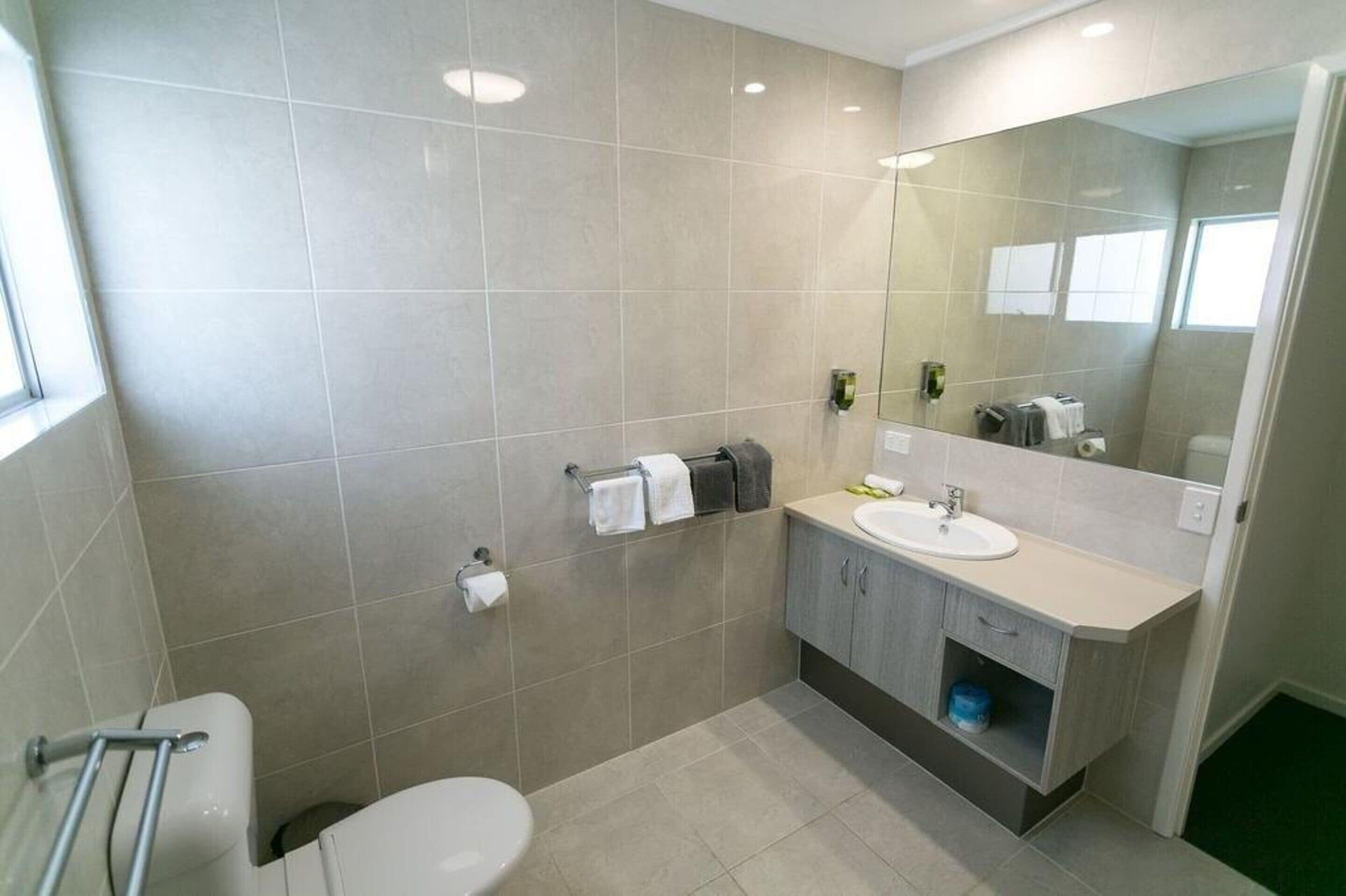 Un bagno moderno con WC, lavandino e specchio.