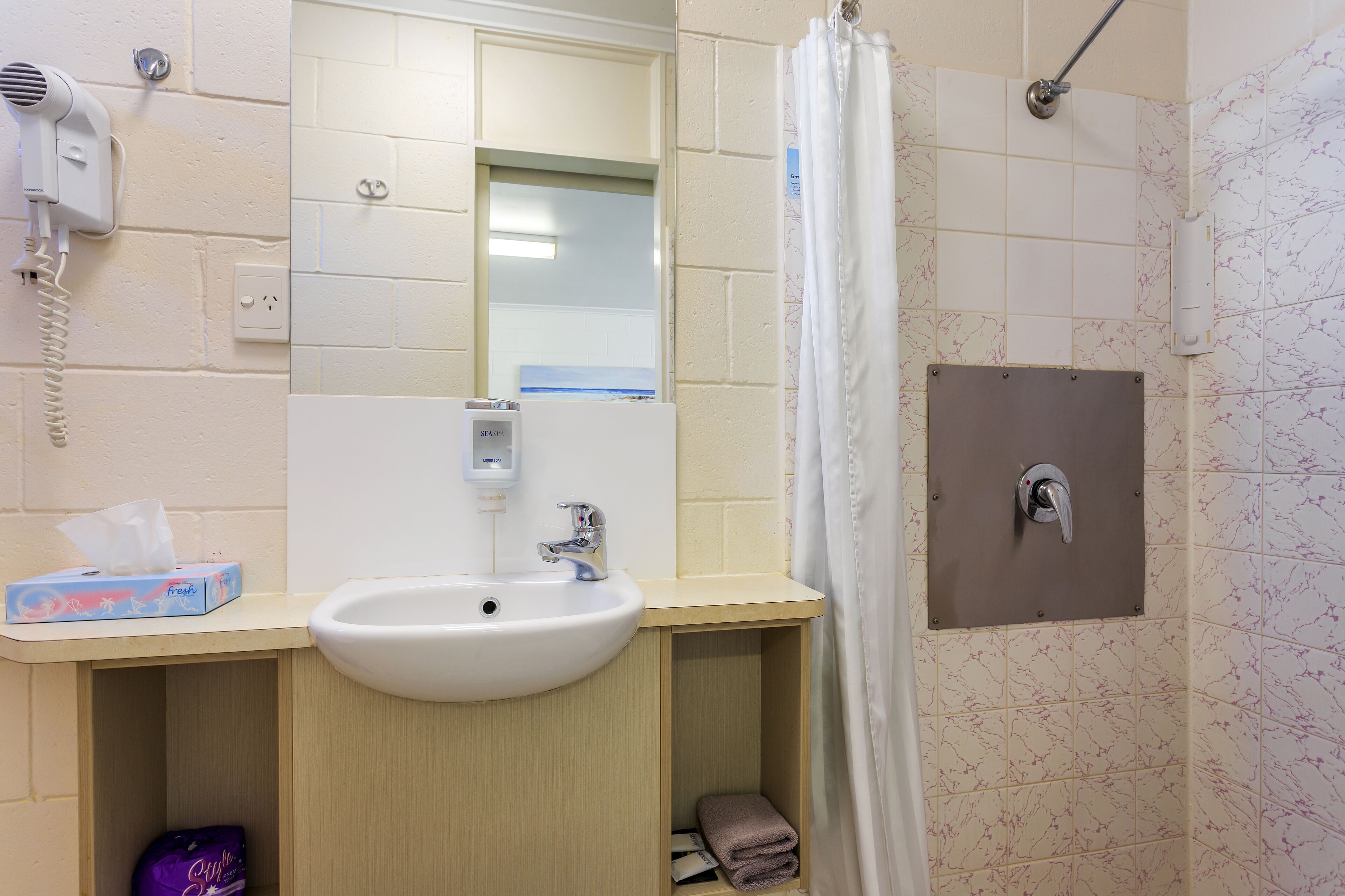 Een badkamer met wastafel, spiegel en douche.
