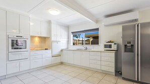A modern kitchen with white cabinets, a stainless steel refrigerator, and a microwave.