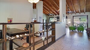 A spacious interior with a high ceiling, wooden beams, a dining area with a table and chairs, and a view through a glass door. - Two Sandals – A Boutique Hotel (St. Thomas)