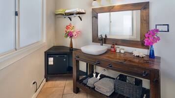A bathroom with a white sink, wooden vanity, and a large mirror.