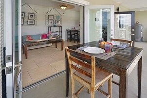 Un comedor con una mesa y sillas de madera, un banco, y una mesa de comedor dispuesta con platos, cuencos y un florero.