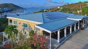 A modern building with a blue roof, solar panels, and a view of a marina with boats. - Two Sandals – A Boutique Hotel (St. Thomas)