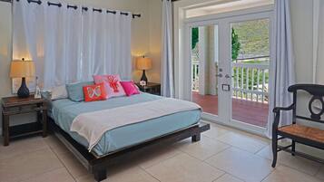 A bedroom with a bed, nightstands, a chair, and a sliding glass door to an outdoor area.