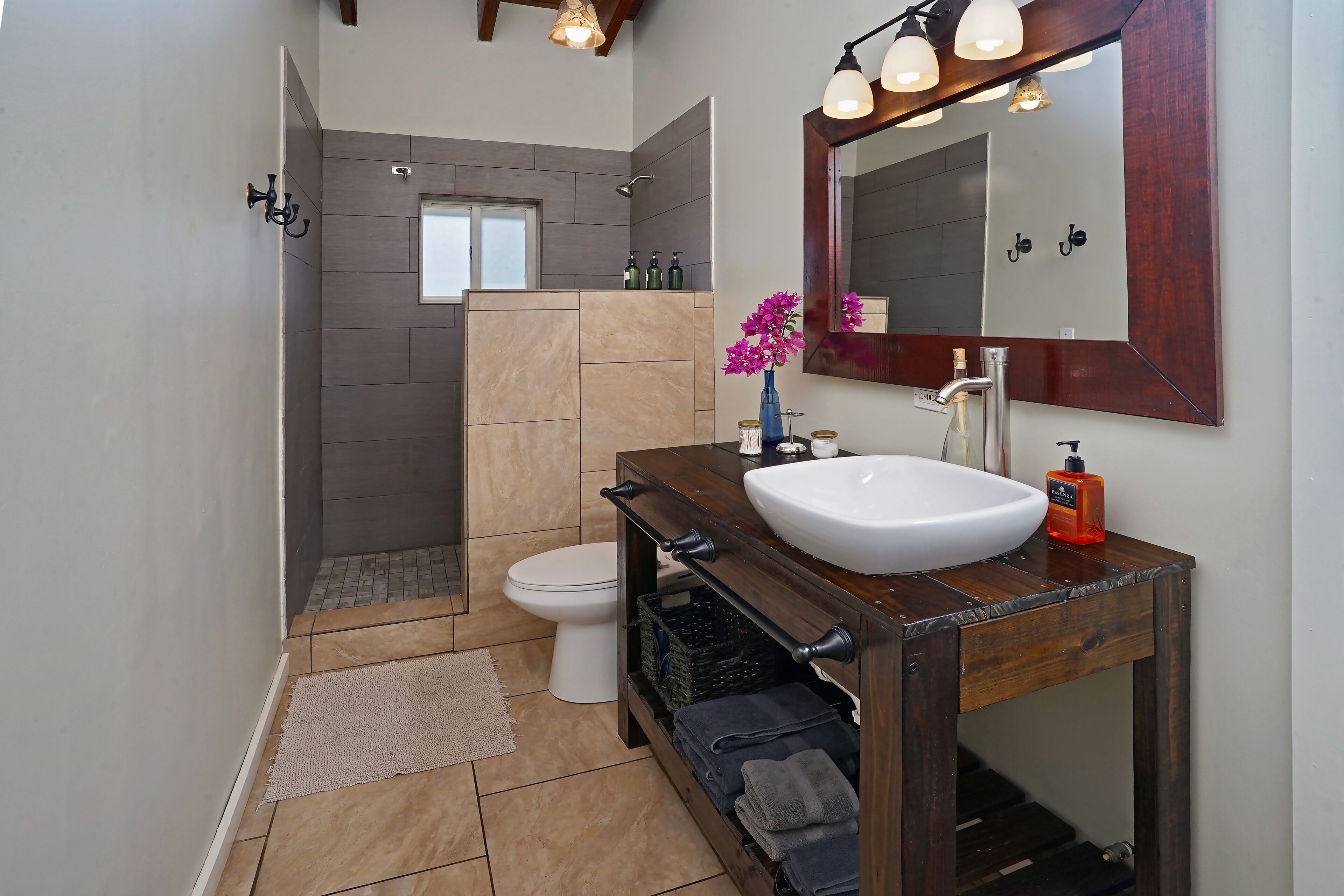 A modern bathroom with a wooden vanity, a large mirror, and a shower area.