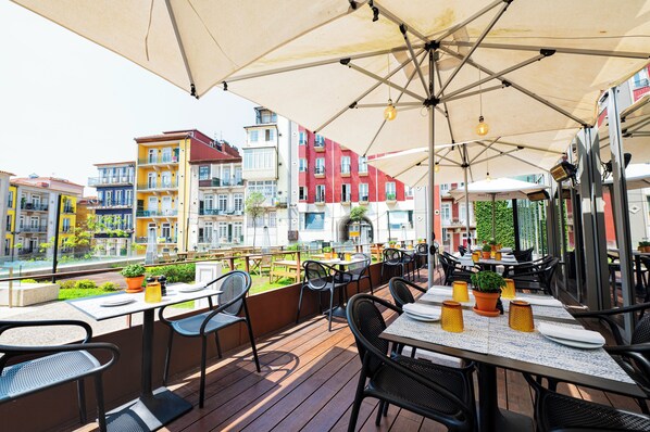 An outdoor dining area with tables and chairs, umbrellas, and potted plants. - InterContinental Porto - Palacio das Cardosas by IHG (Porto)