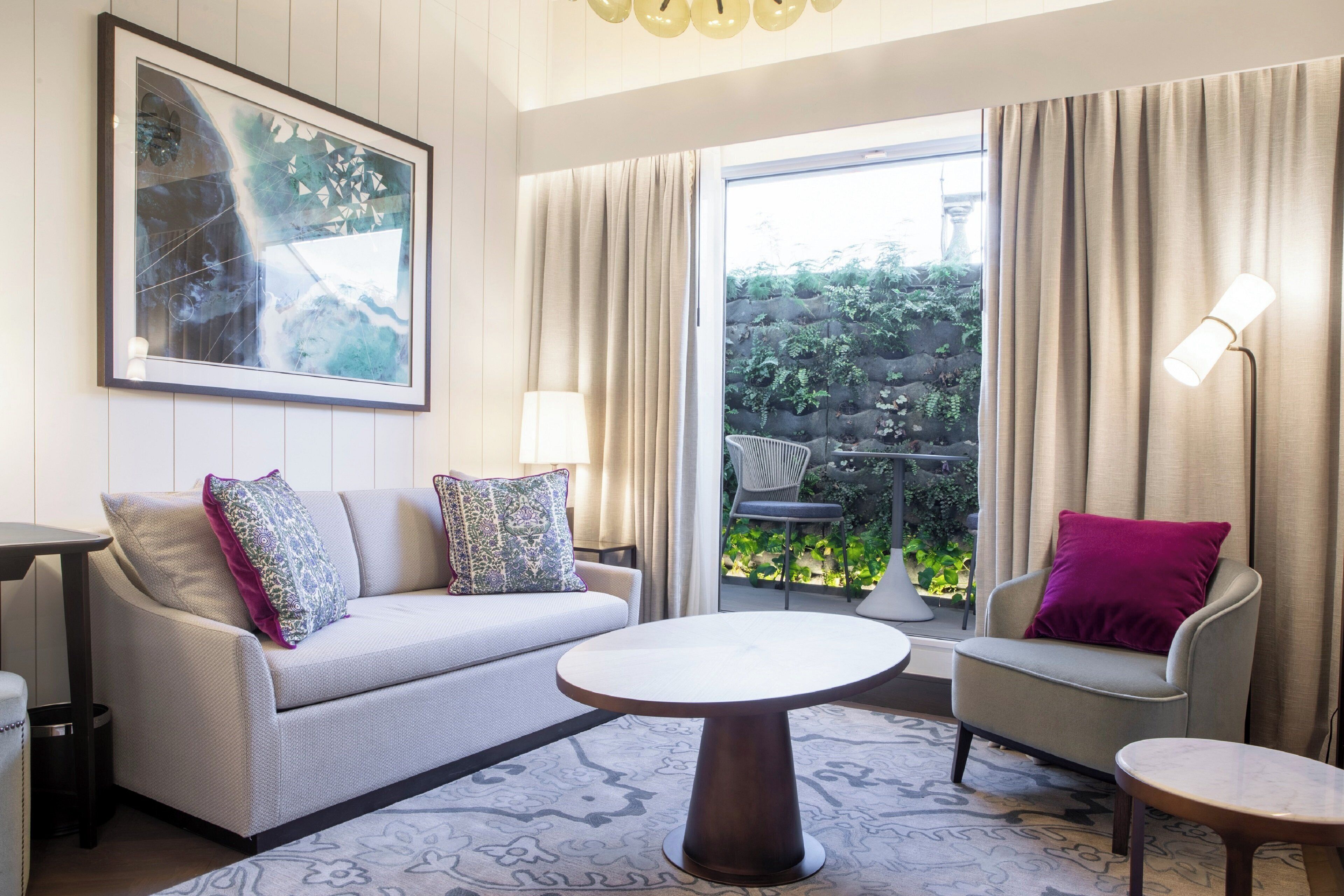 A modern living room with a sofa, armchairs, a coffee table, and a large window with curtains.