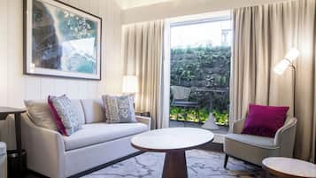 A modern living room with a sofa, armchairs, a coffee table, and a large window with curtains.