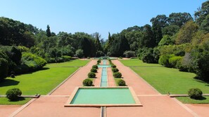 A formal garden with a central water feature, symmetrical pathways, and well-maintained lawns.