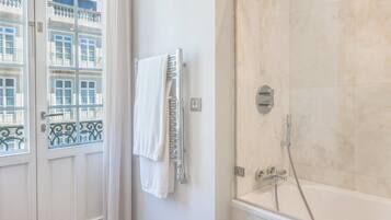 A bathroom with a bathtub, a towel rack with a towel, and a window with a view of buildings.