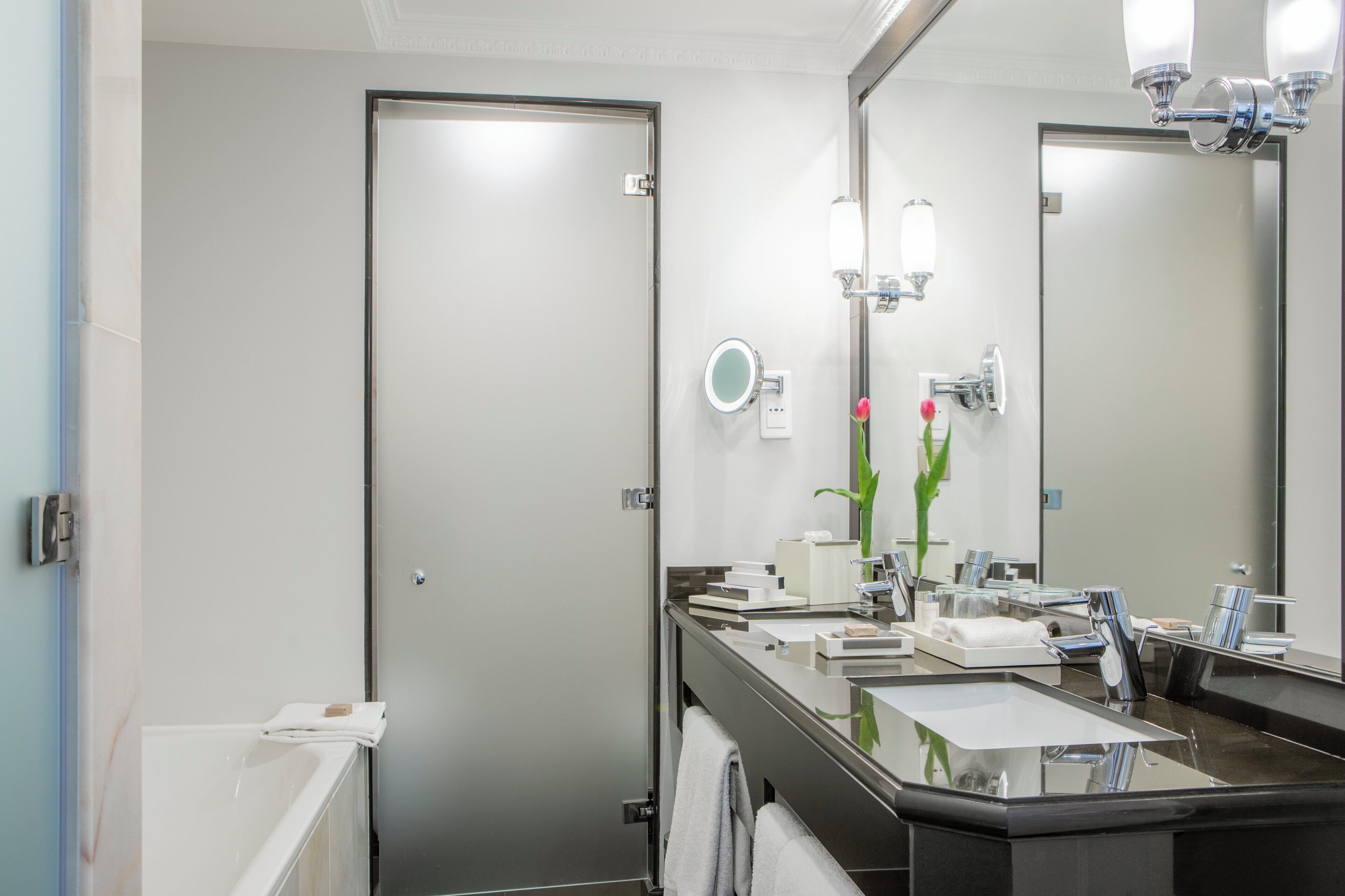 Un baño moderno con un espejo grande, un lavabo y una ducha.