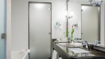Un baño moderno con un espejo grande, un lavabo y una ducha.