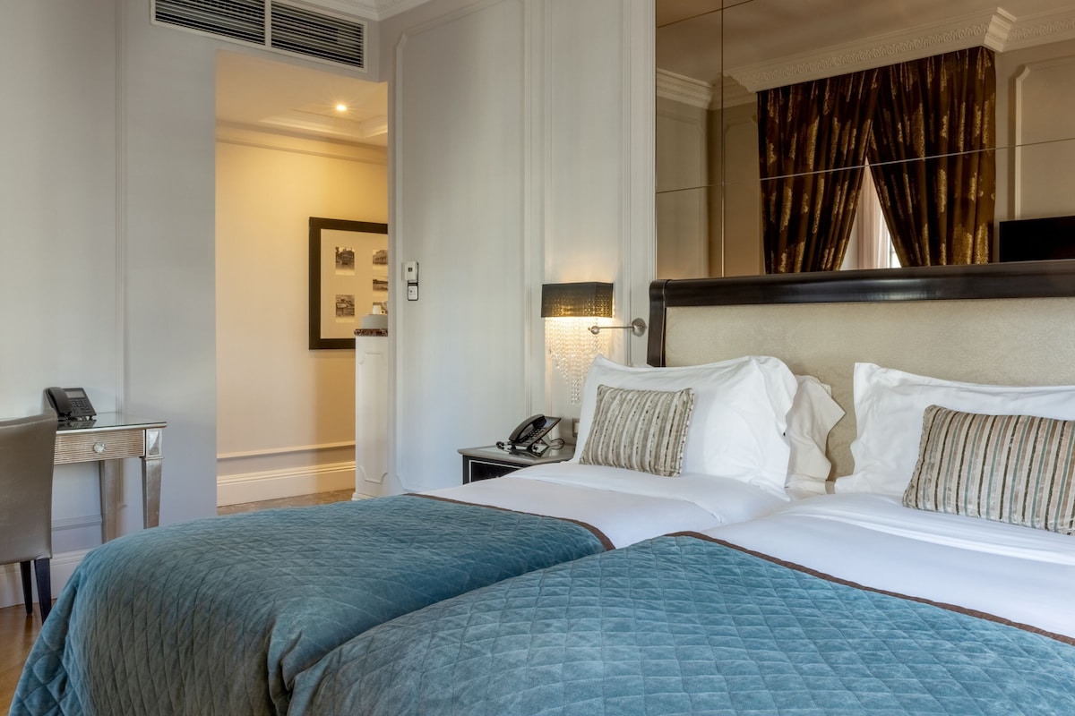 A hotel room with a large bed, two bedside tables, a desk, and a mirror.