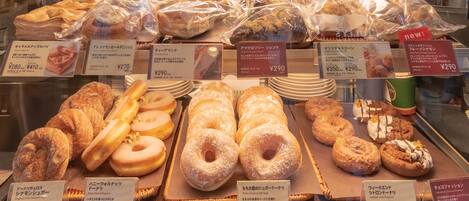Mostrador de una panadería con diversos pasteles y panes, cada uno con su precio indicado.
