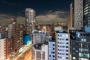 A cityscape at night with high-rise buildings, illuminated windows, and a busy street. - E Hotel Higashi Shinjuku (Tokyo)