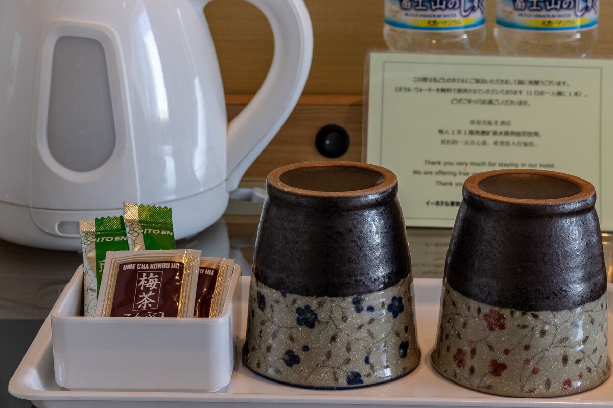 A tray with tea packets, a white kettle, and ceramic containers with a floral pattern.