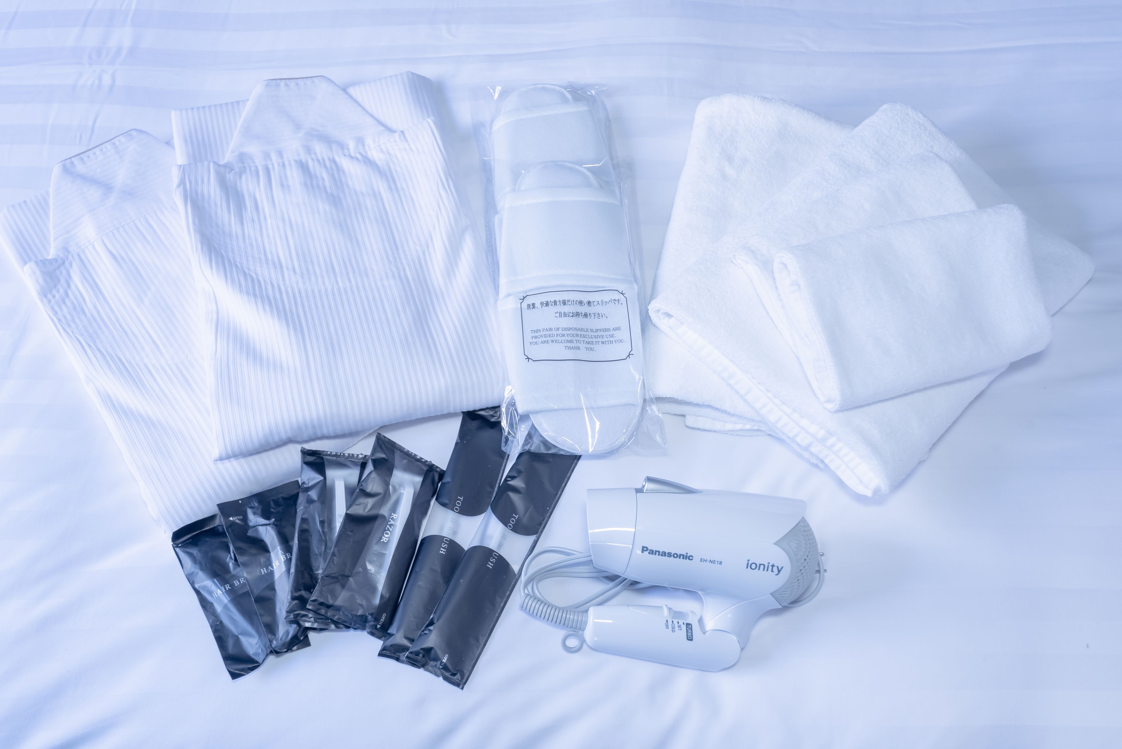A neatly arranged set of toiletries and a hair dryer on a bed.