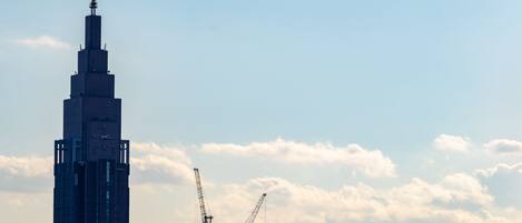 A tall skyscraper with a clock, surrounded by construction cranes and other buildings.