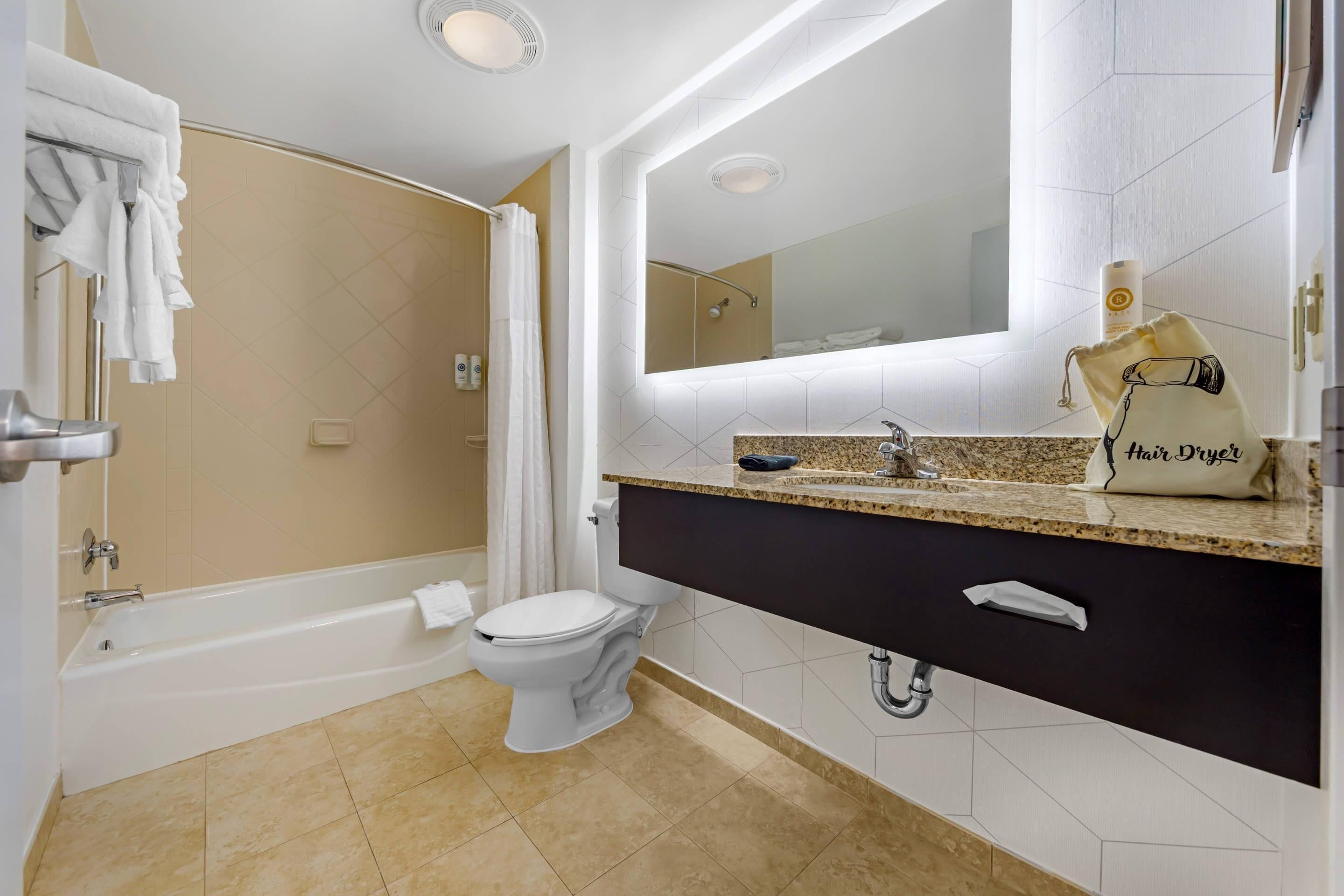 Un baño moderno con bañera, inodoro y tocador con espejo.