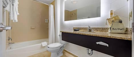 Un baño moderno con bañera, inodoro y tocador con espejo.