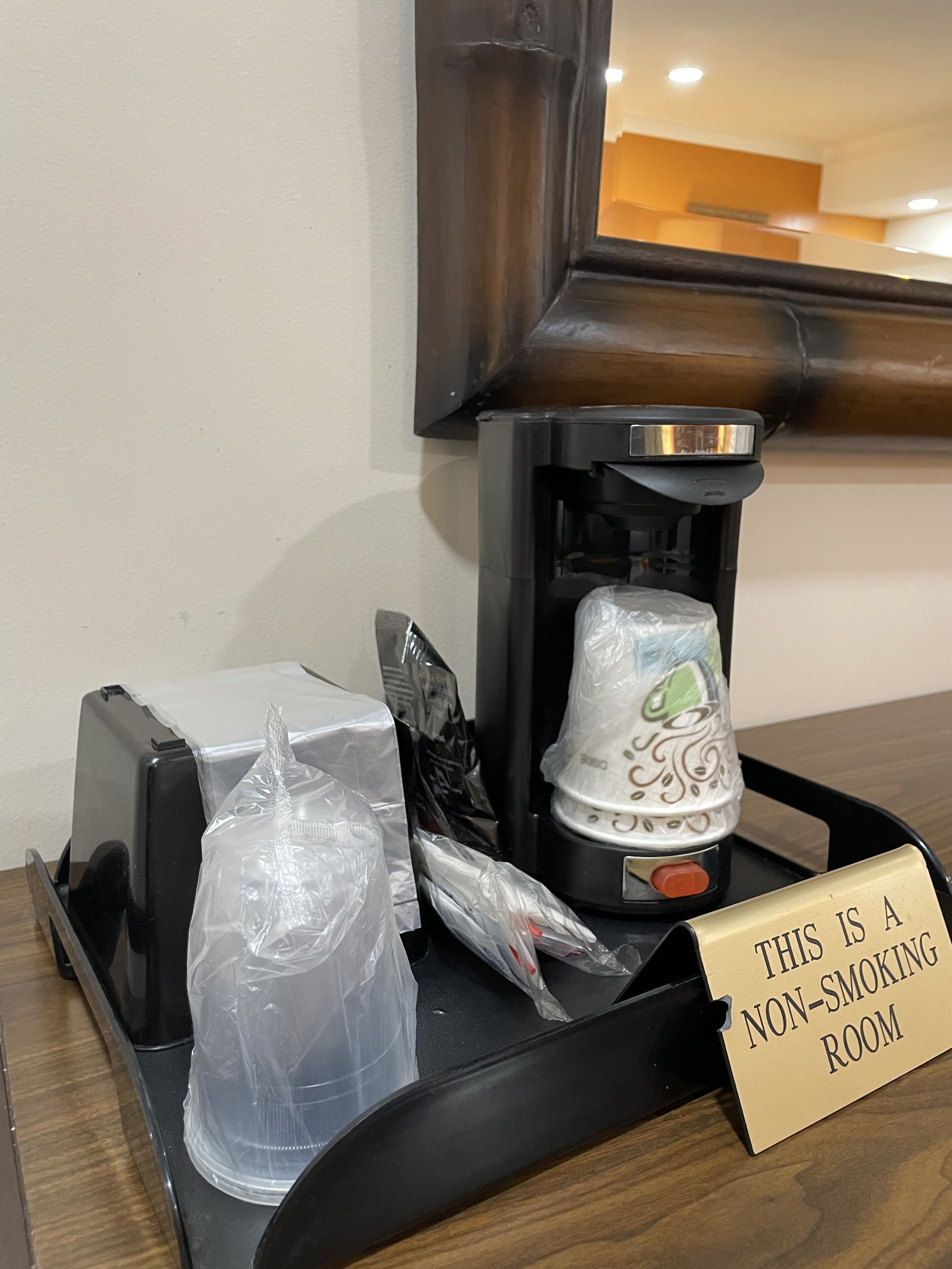 Une pancarte indiquant qu’il s’agit d’une chambre non-fumeur, une machine à café, un grille-pain et un récipient en plastique sur un plateau.