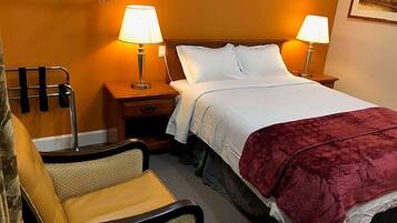 A hotel room with a bed, two bedside lamps, a chair, and a nightstand.