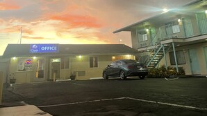 Un edificio con un cartel que dice "Oasis Office" y un coche estacionado frente a  él.